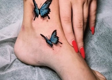 Vibrant butterfly tattoos on an ankle at BarberSmiths Tattoo Studio, London, England, GB.