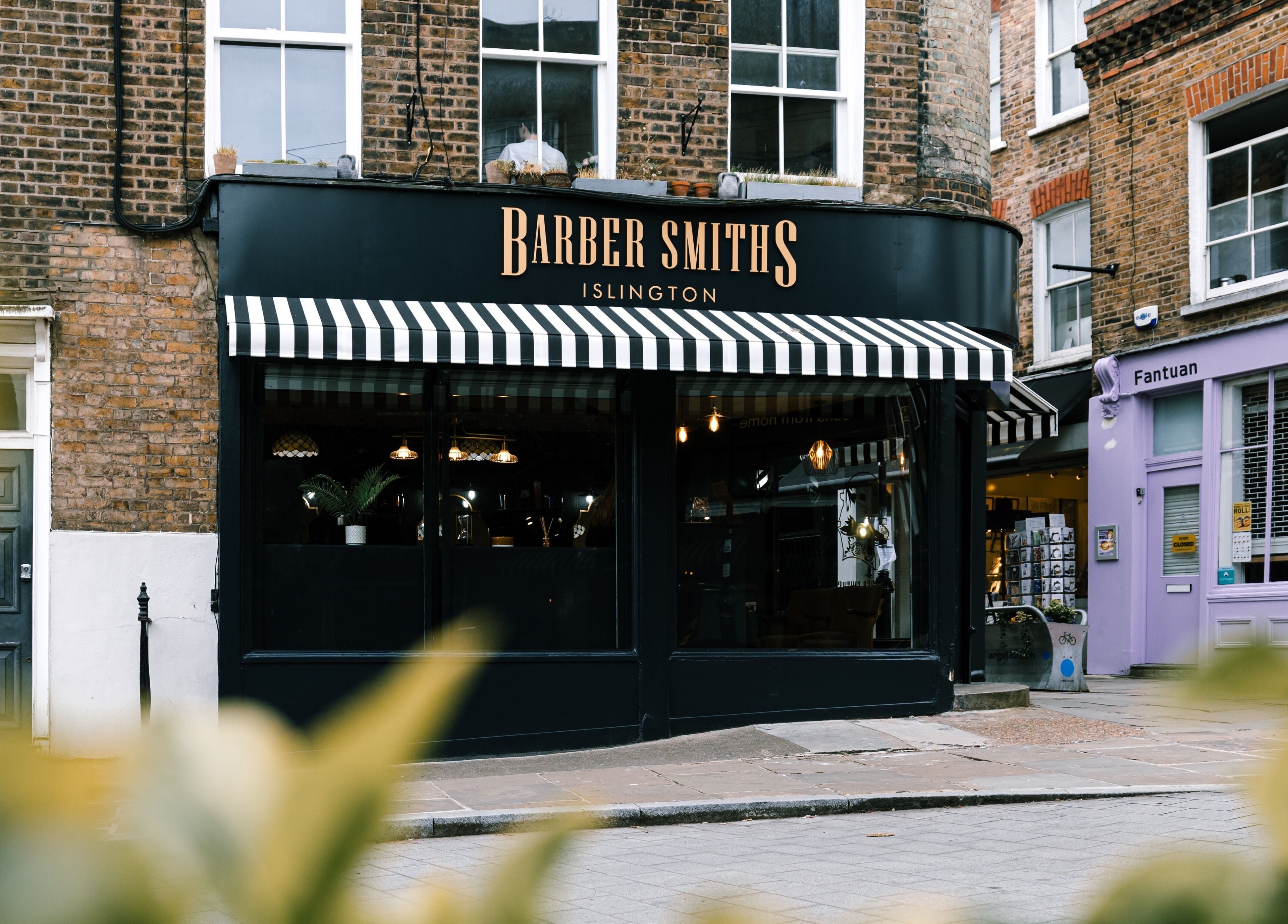 BarberSmiths Islington storefront featuring striped awning in London, England, GB, inviting and stylish.