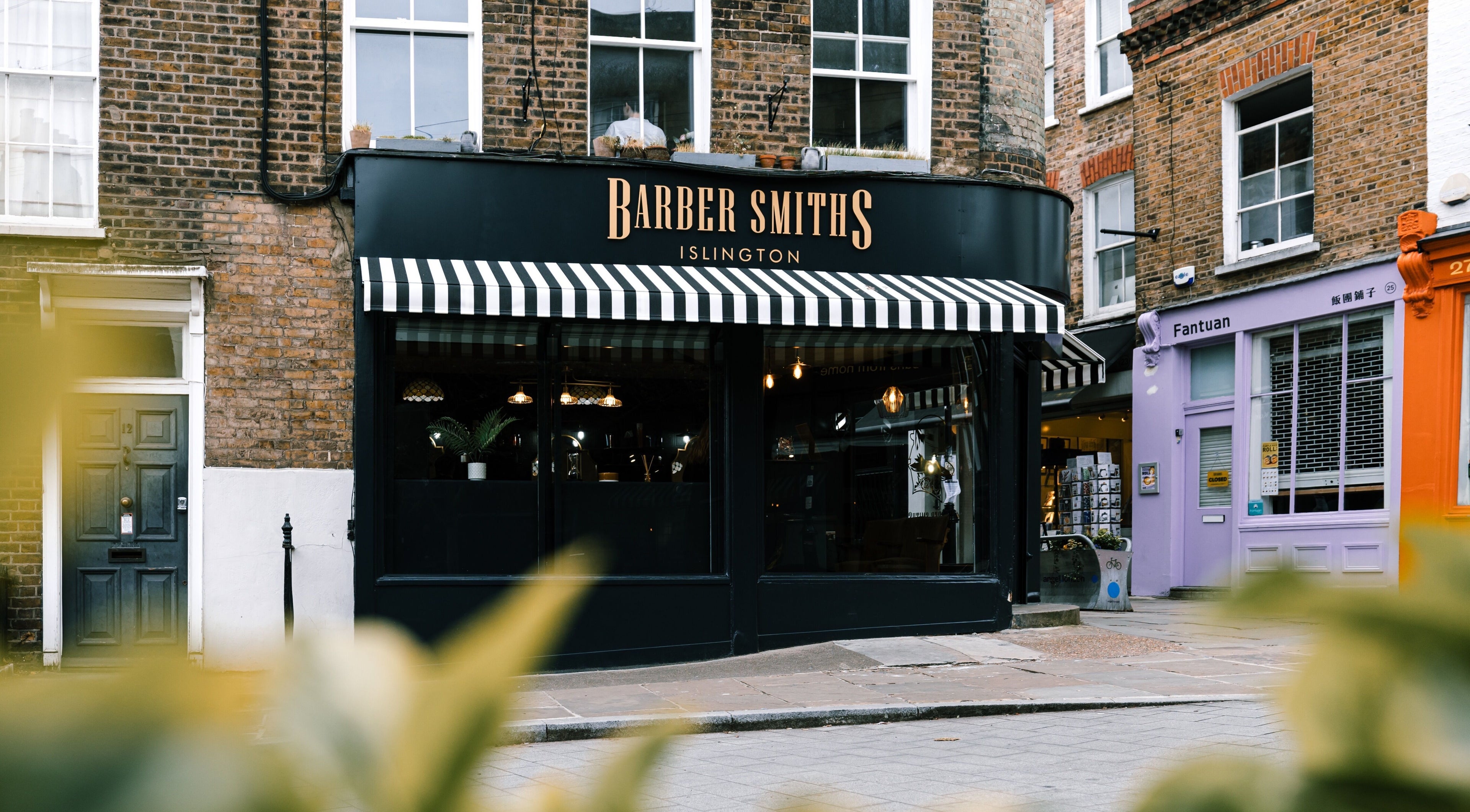 BarberSmiths Islington storefront featuring striped awning in London, England, GB, inviting and stylish.