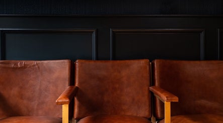Warm brown leather chairs at BarberSmiths Notting Hill in London, England, GB, offer a stylish waiting area.