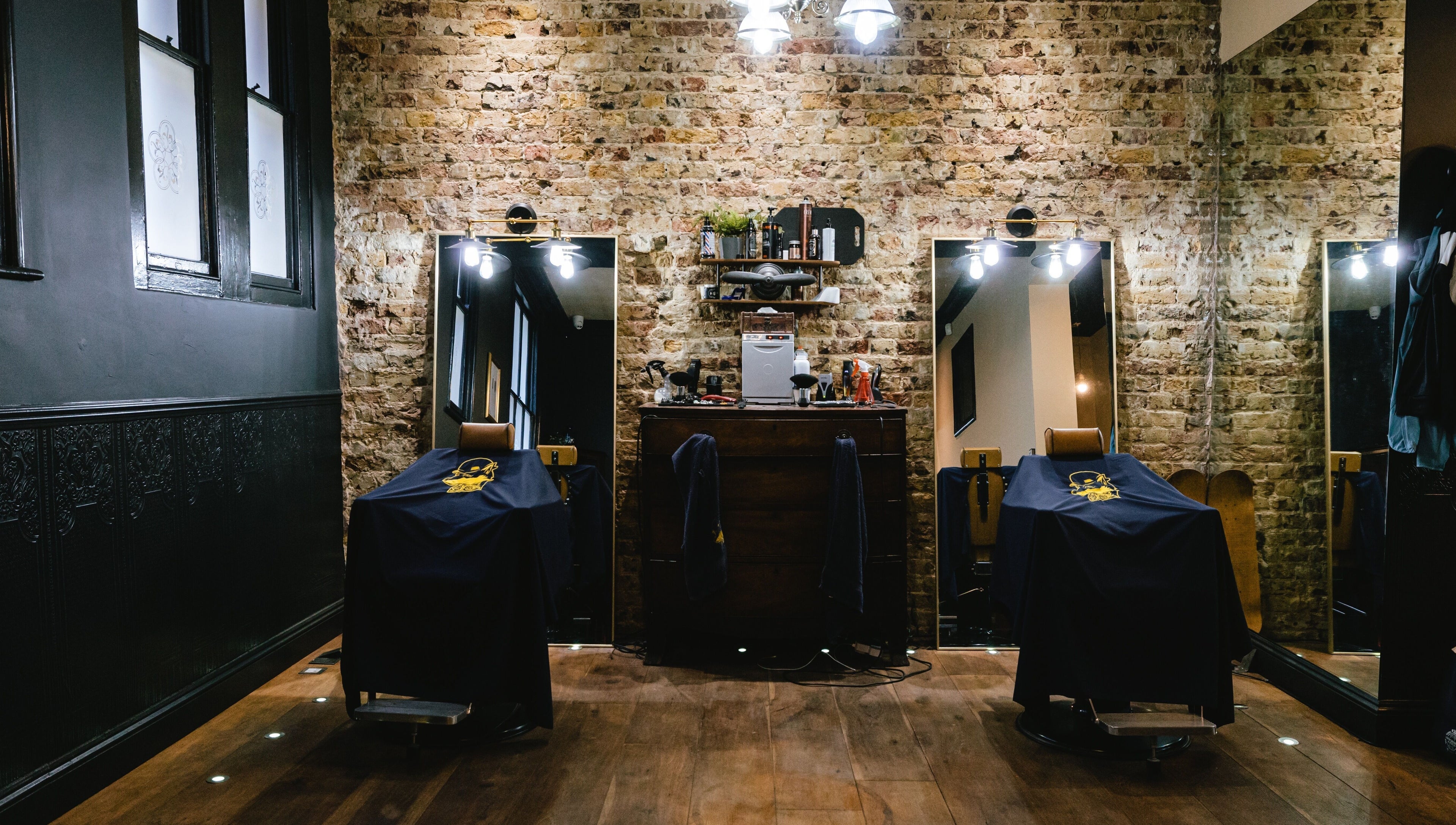 Chic interior of BarberSmiths Shoreditch, London, England, GB, highlighting exposed brick and vintage barber chairs.