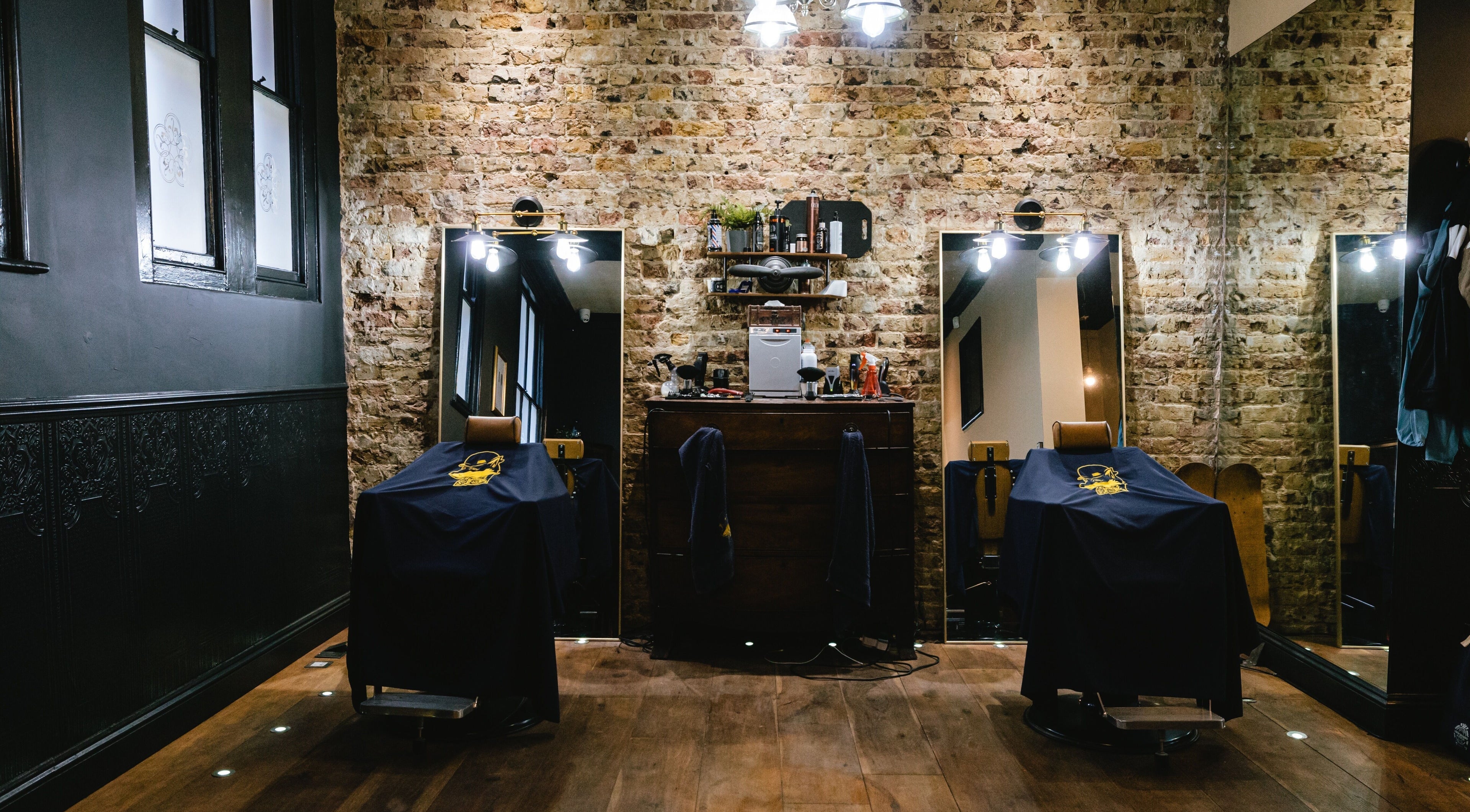Chic interior of BarberSmiths Shoreditch, London, England, GB, highlighting exposed brick and vintage barber chairs.