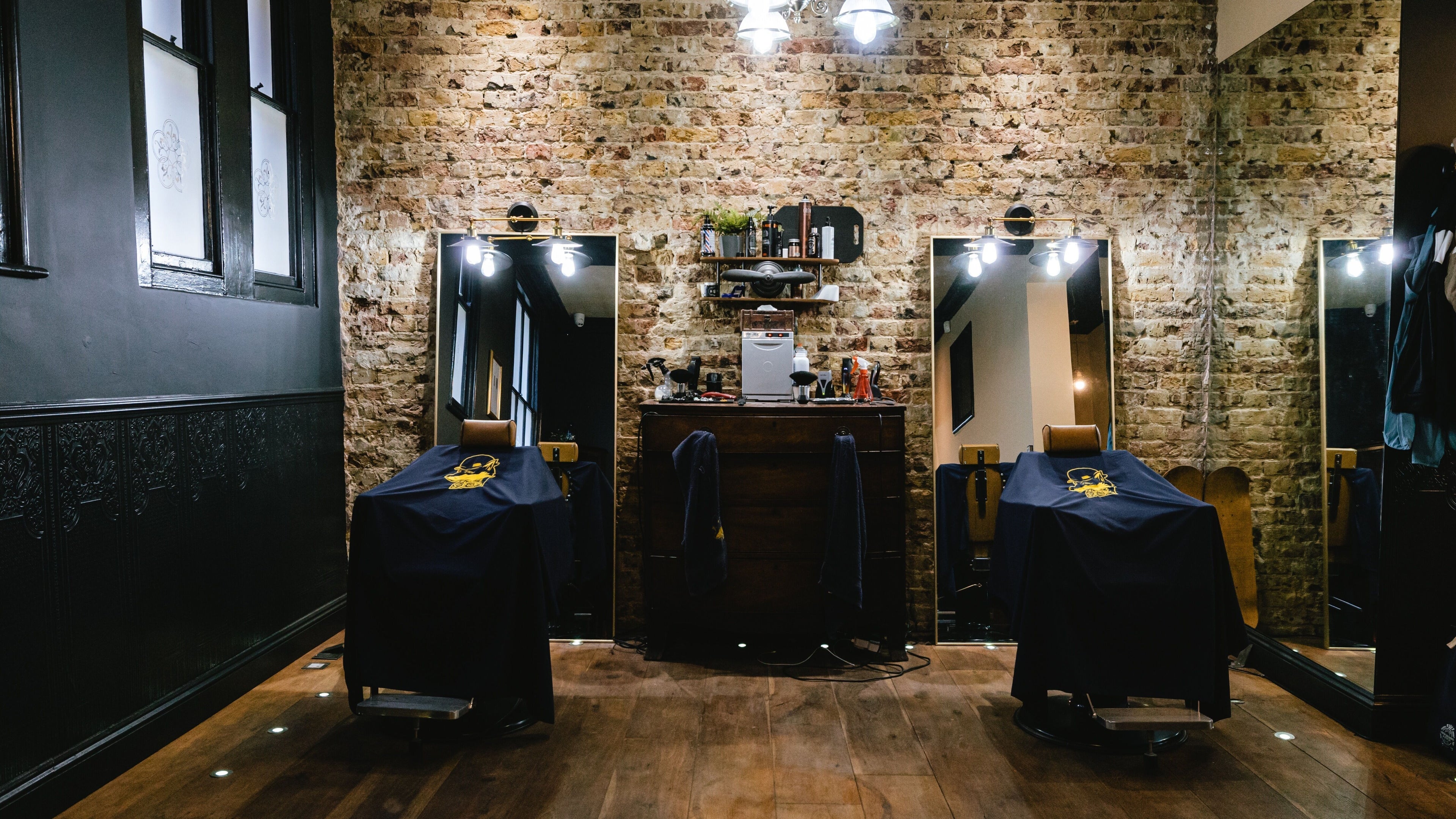 Chic interior of BarberSmiths Shoreditch, London, England, GB, highlighting exposed brick and vintage barber chairs.