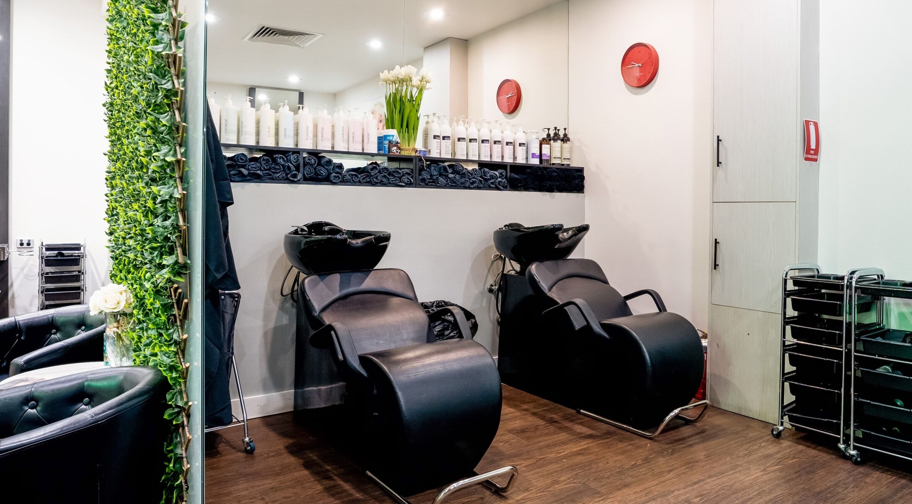 Stylish wash stations at Bellamane Hair Studio in Melbourne, Victoria, AU, featuring sleek black chairs and modern decor.