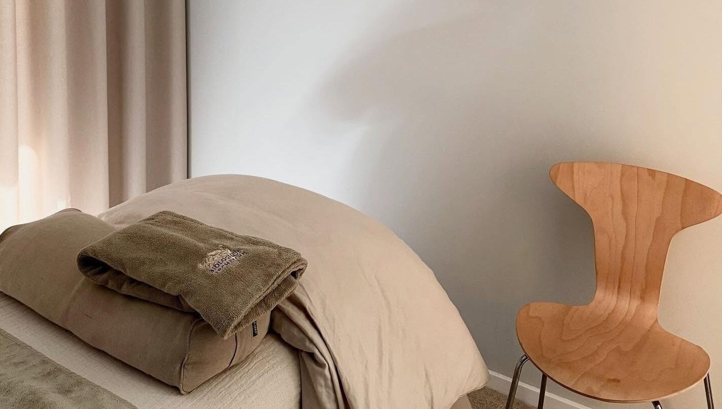 Rolig massageplads på Allure Copenhagen, Frederiksberg, DK med bløde håndklæder og en træstol.