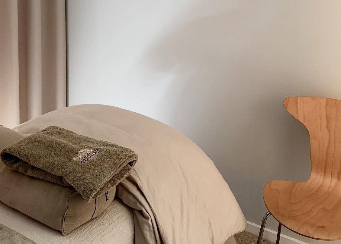 Rolig massageplads på Allure Copenhagen, Frederiksberg, DK med bløde håndklæder og en træstol.