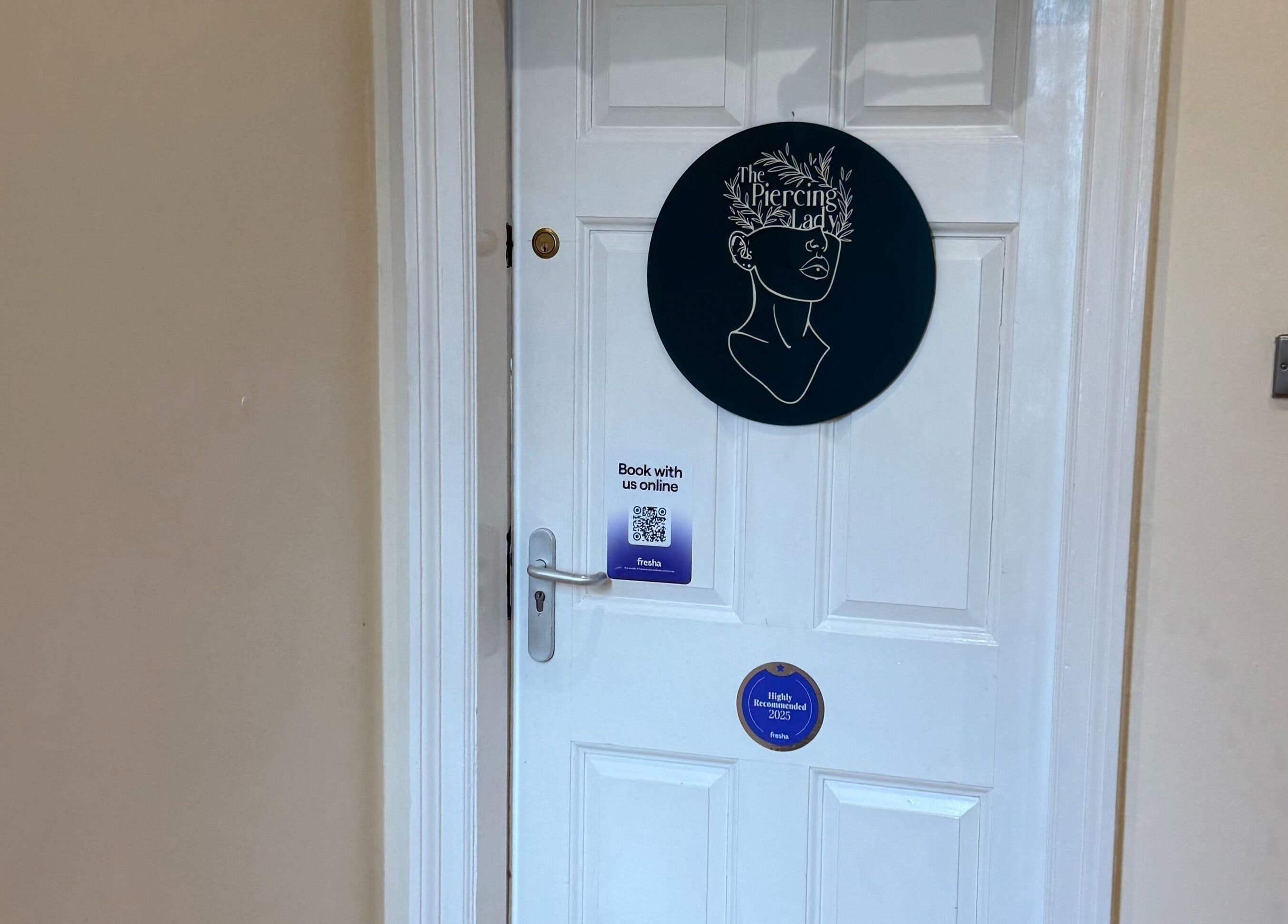 Entrance to The Piercing Lady in Darlington, England, GB, featuring a unique artistic sign on the door.