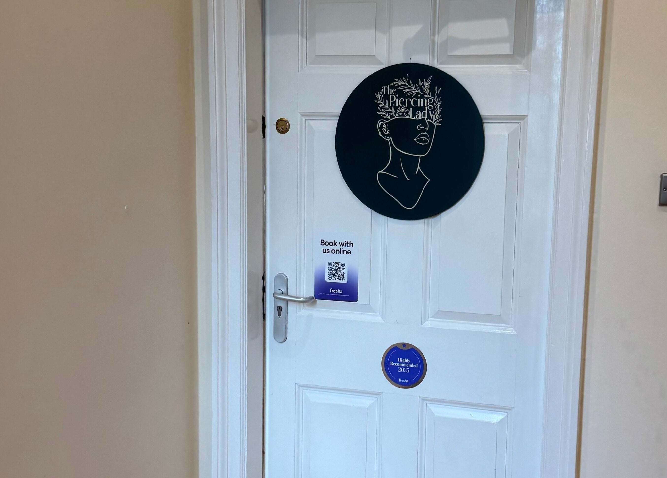 Entrance to The Piercing Lady in Darlington, England, GB, featuring a unique artistic sign on the door.