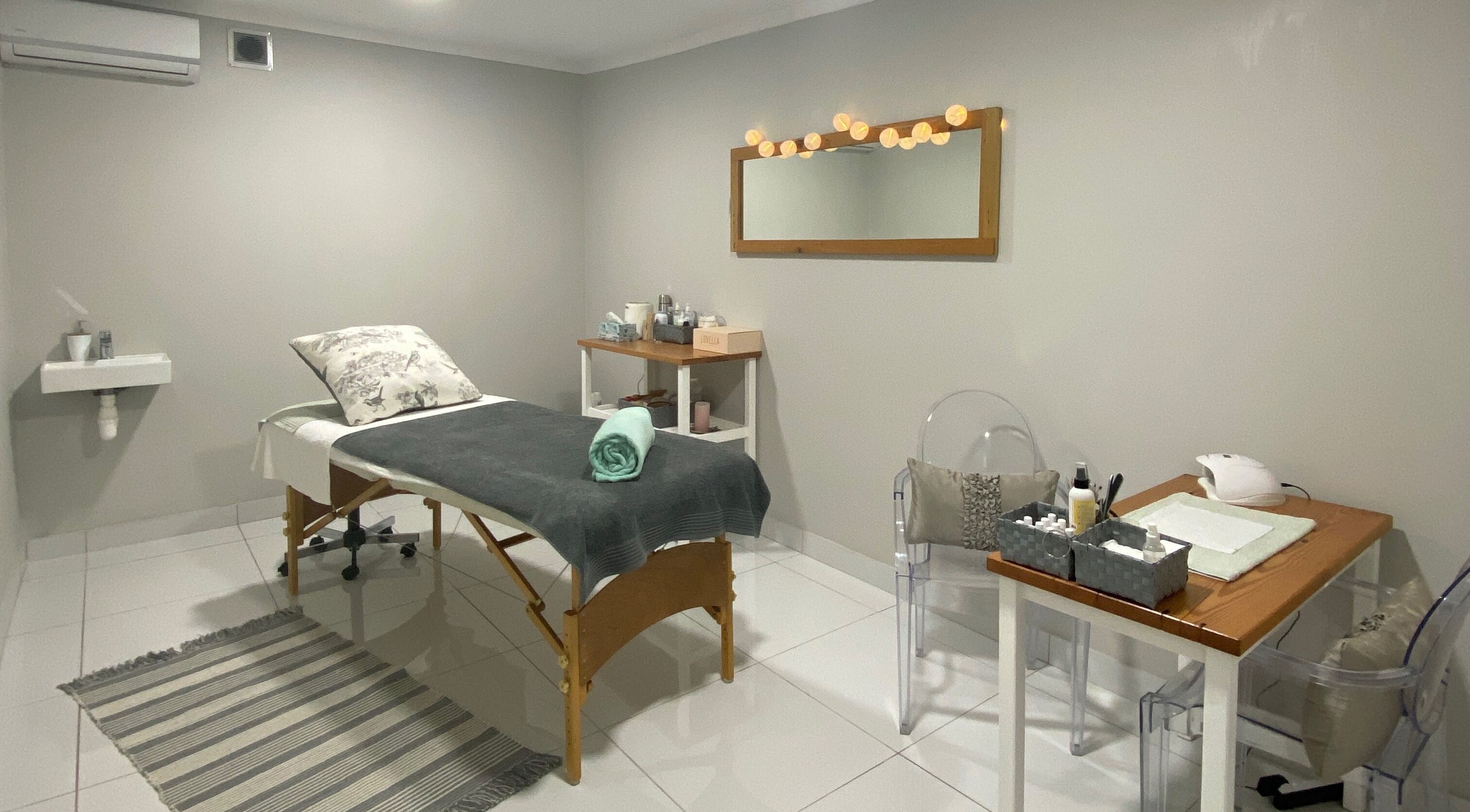 Elegant spa room at The Powder Room, Port Elizabeth, Eastern Cape, ZA, featuring a massage bed and stylish decor.