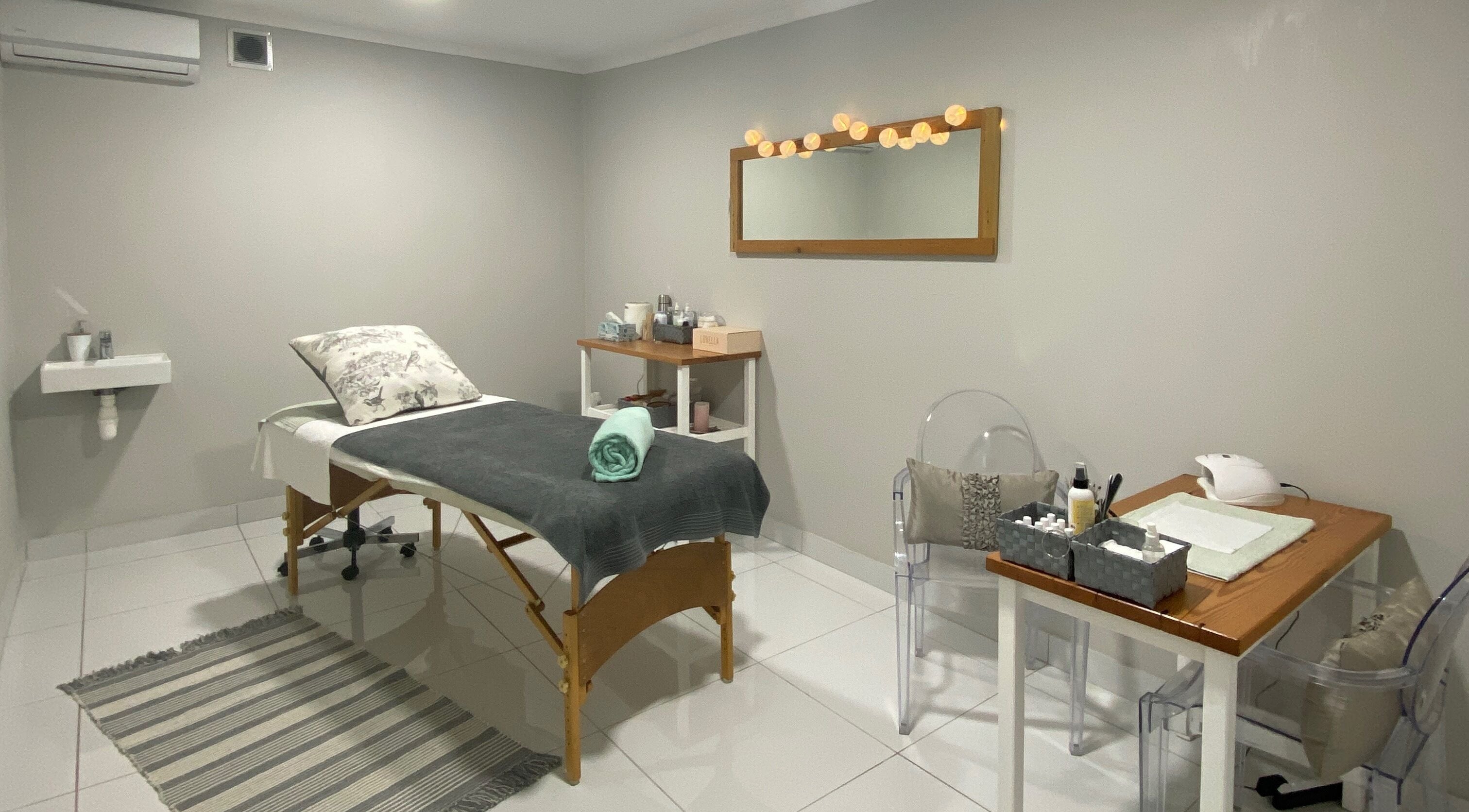 Elegant spa room at The Powder Room, Port Elizabeth, Eastern Cape, ZA, featuring a massage bed and stylish decor.