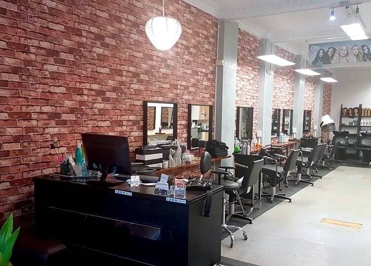 Interior of Top Katz salon in Wynnum, Queensland, AU featuring styling stations against a brick wall.
