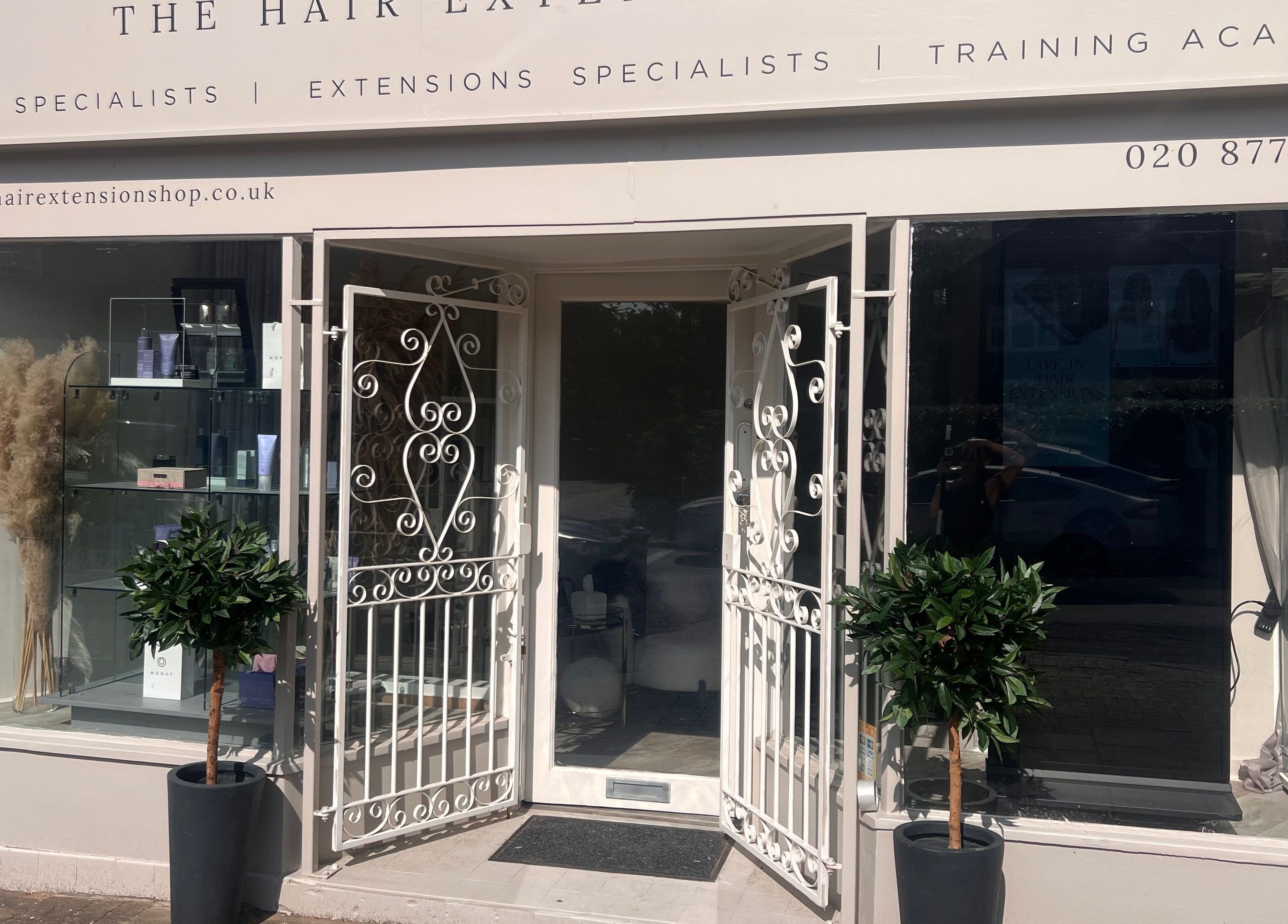 Front view of The Hair Extension Shop in West Wickham, England, GB showcasing elegant white doors and plants.