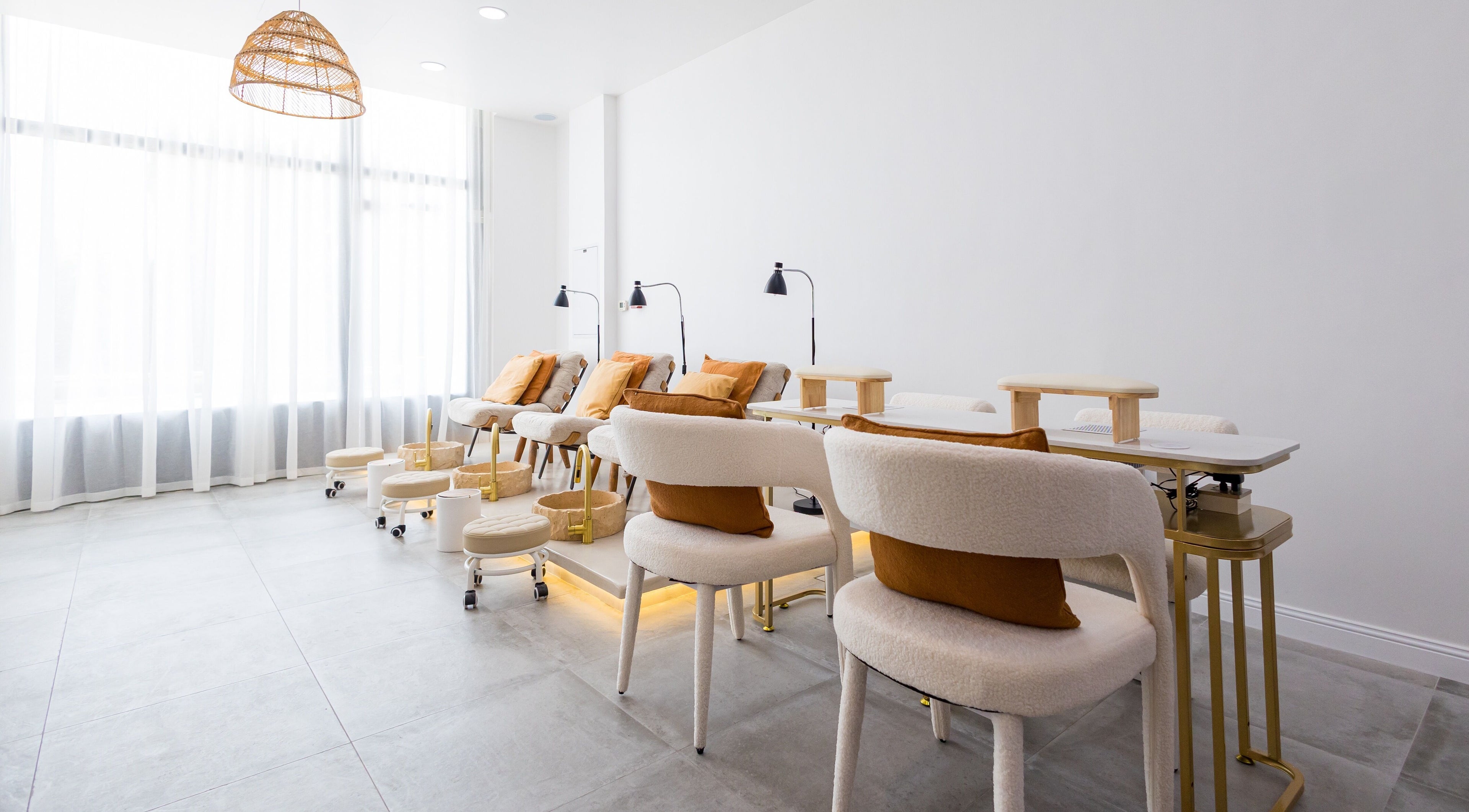 Modern and serene nail area at The Den Salon in Dubai, AE with plush seating and ambient lighting.