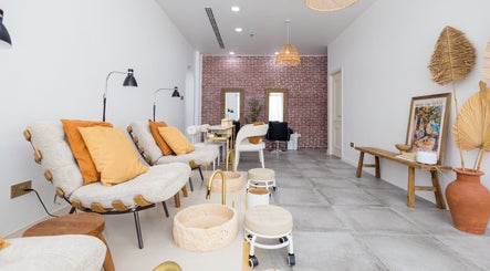 Relaxing seating area at The Den Salon, Dubai, AE, features comfortable chairs and elegant decor.