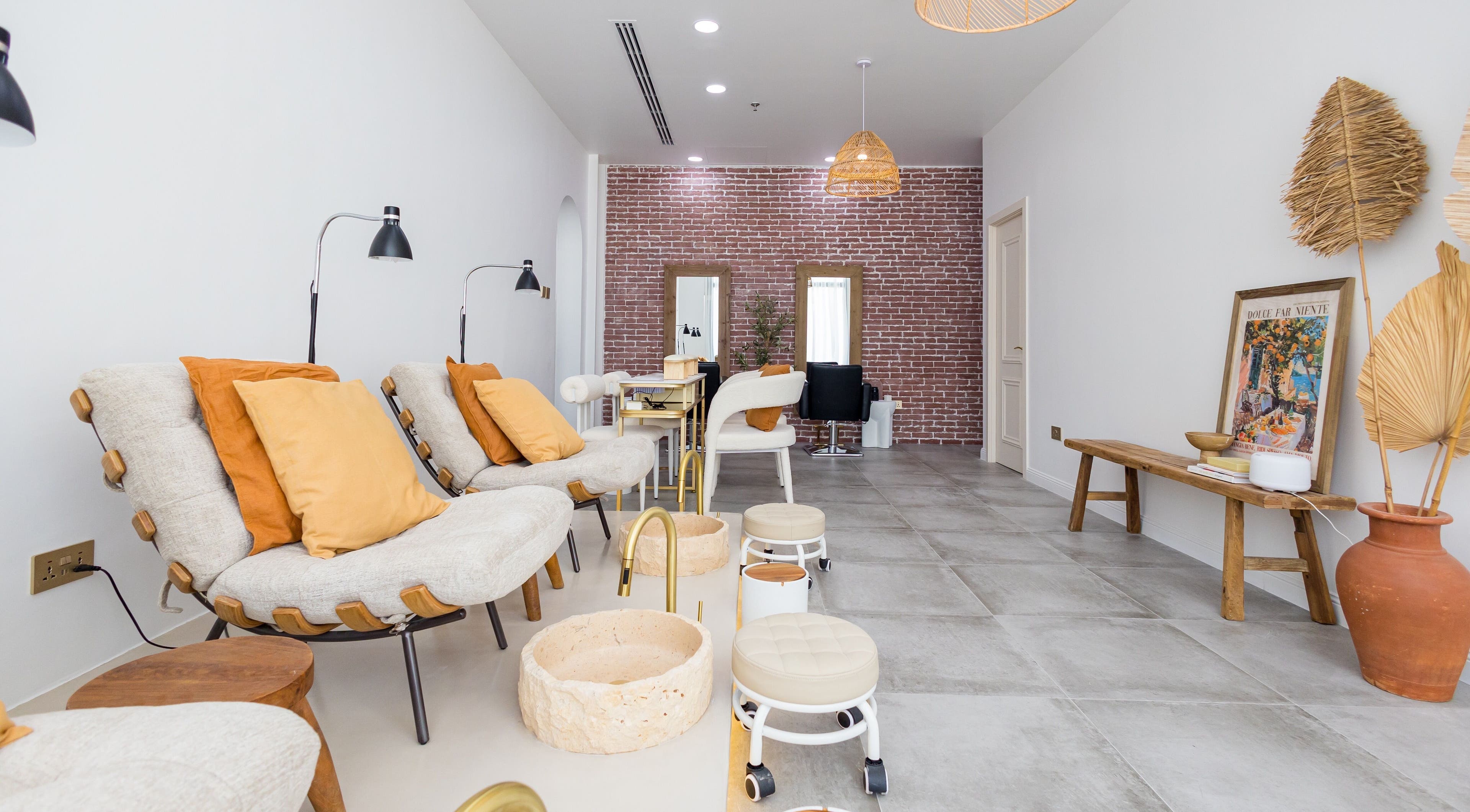 Relaxing seating area at The Den Salon, Dubai, AE, features comfortable chairs and elegant decor.