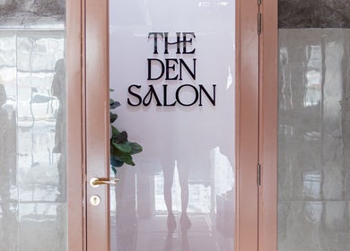 Entrance of The Den Salon in Dubai, AE with a modern glass door and sleek design.