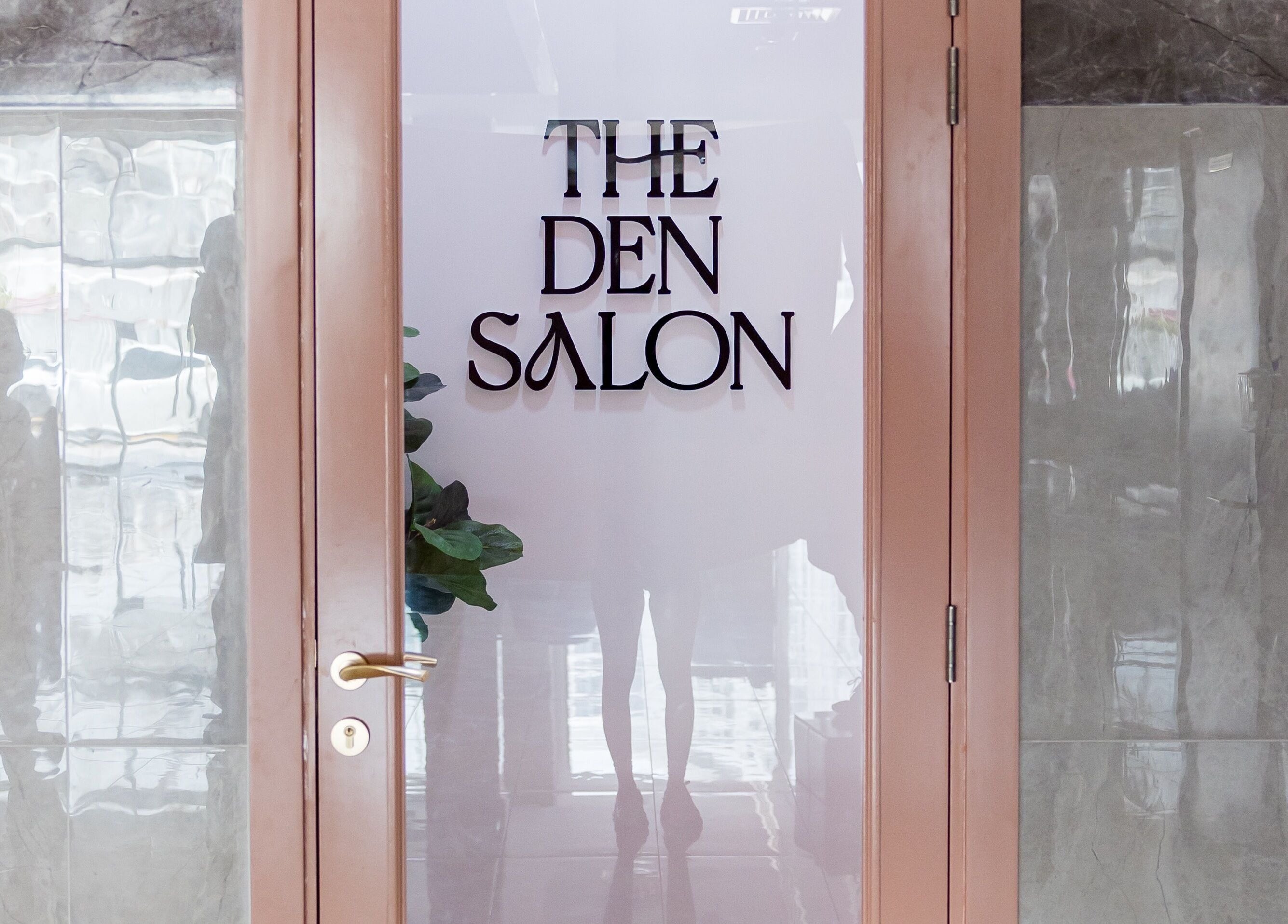 Entrance of The Den Salon in Dubai, AE with a modern glass door and sleek design.
