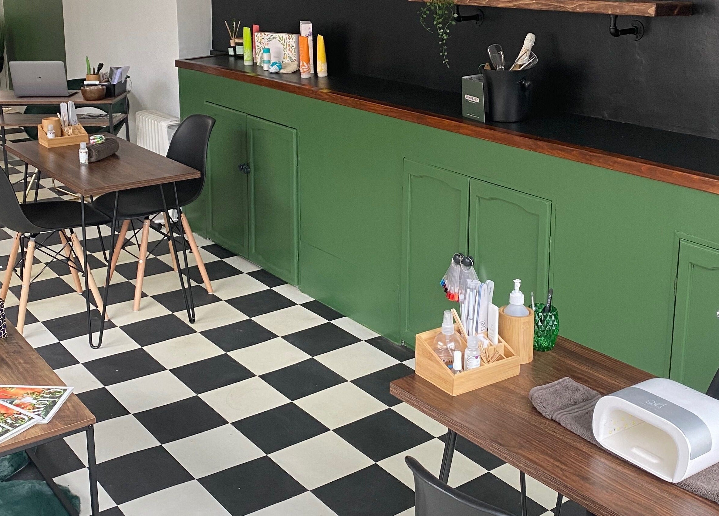 Modern interior of Station Beauty in Whitehill, England, featuring stylish tables and checkered floor.