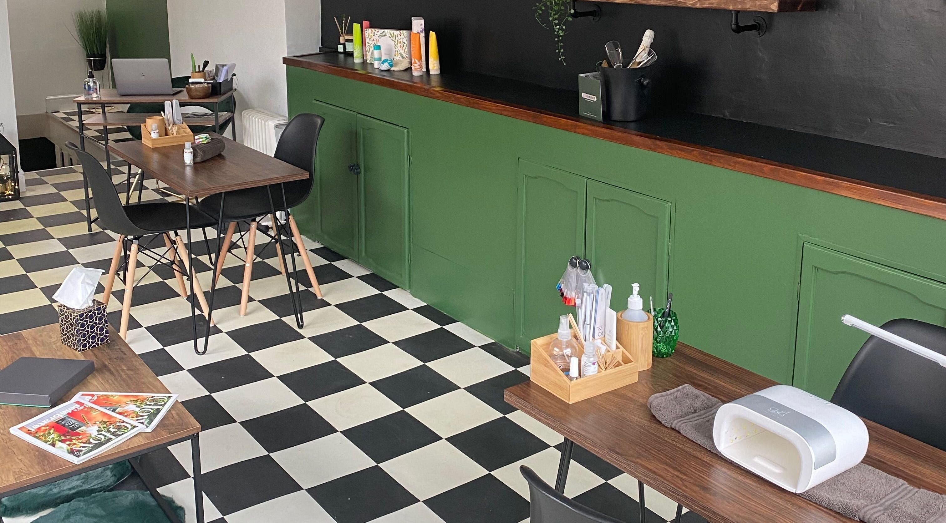 Modern interior of Station Beauty in Whitehill, England, featuring stylish tables and checkered floor.