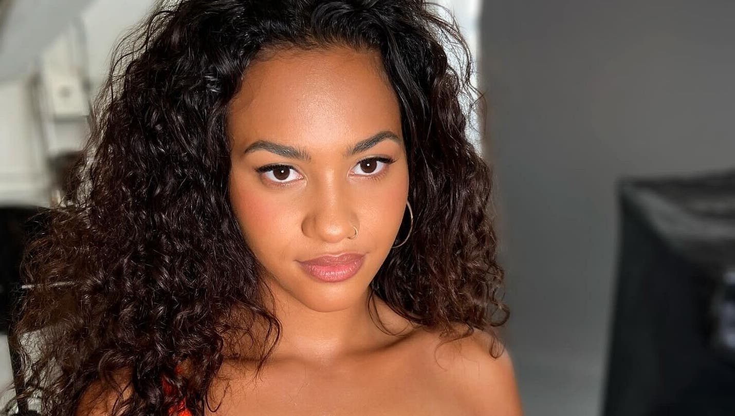 A woman showcasing radiant makeup and curly hair, epitomizing beauty at By Rayner, Warrington, GB.