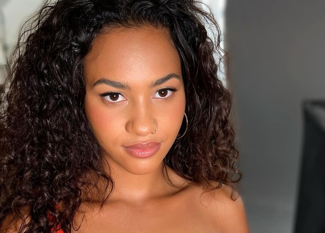 A woman showcasing radiant makeup and curly hair, epitomizing beauty at By Rayner, Warrington, GB.