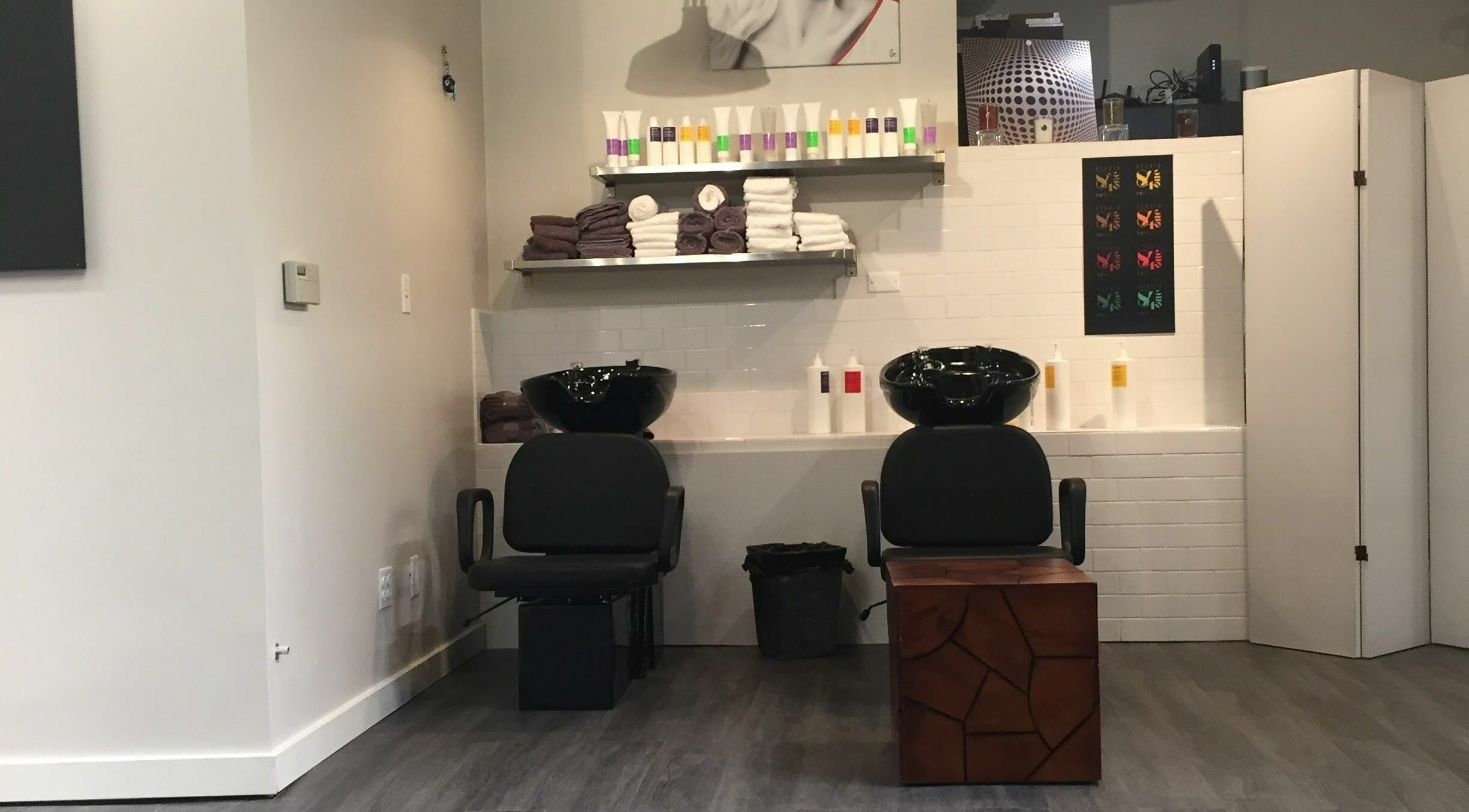 Modern hair wash station at Studio 84one in Chicago, Illinois, US, featuring sleek chairs and shelving.