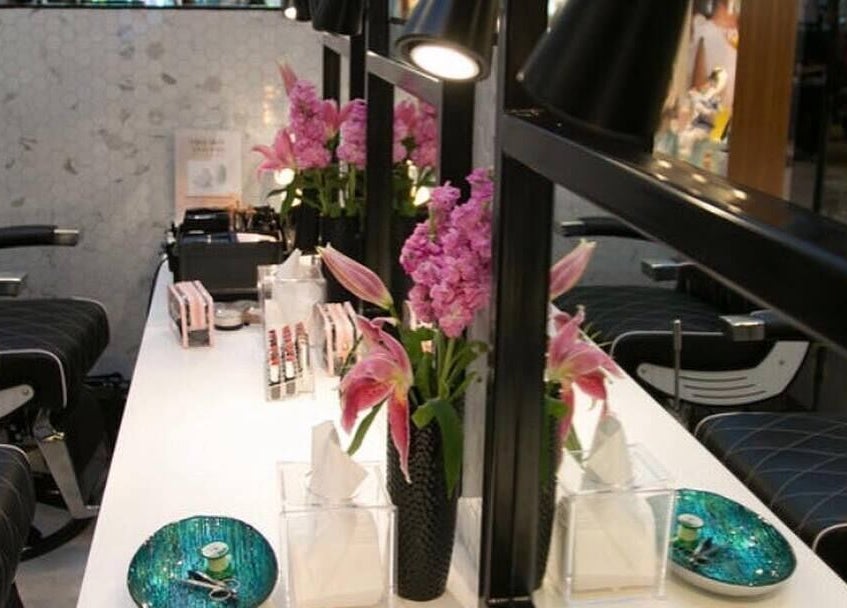 Chic styling station at Aarch The Eyebrow Bar (Rubbina's Beauty and Brow Bar), Auckland, NZ, adorned with pink flowers.