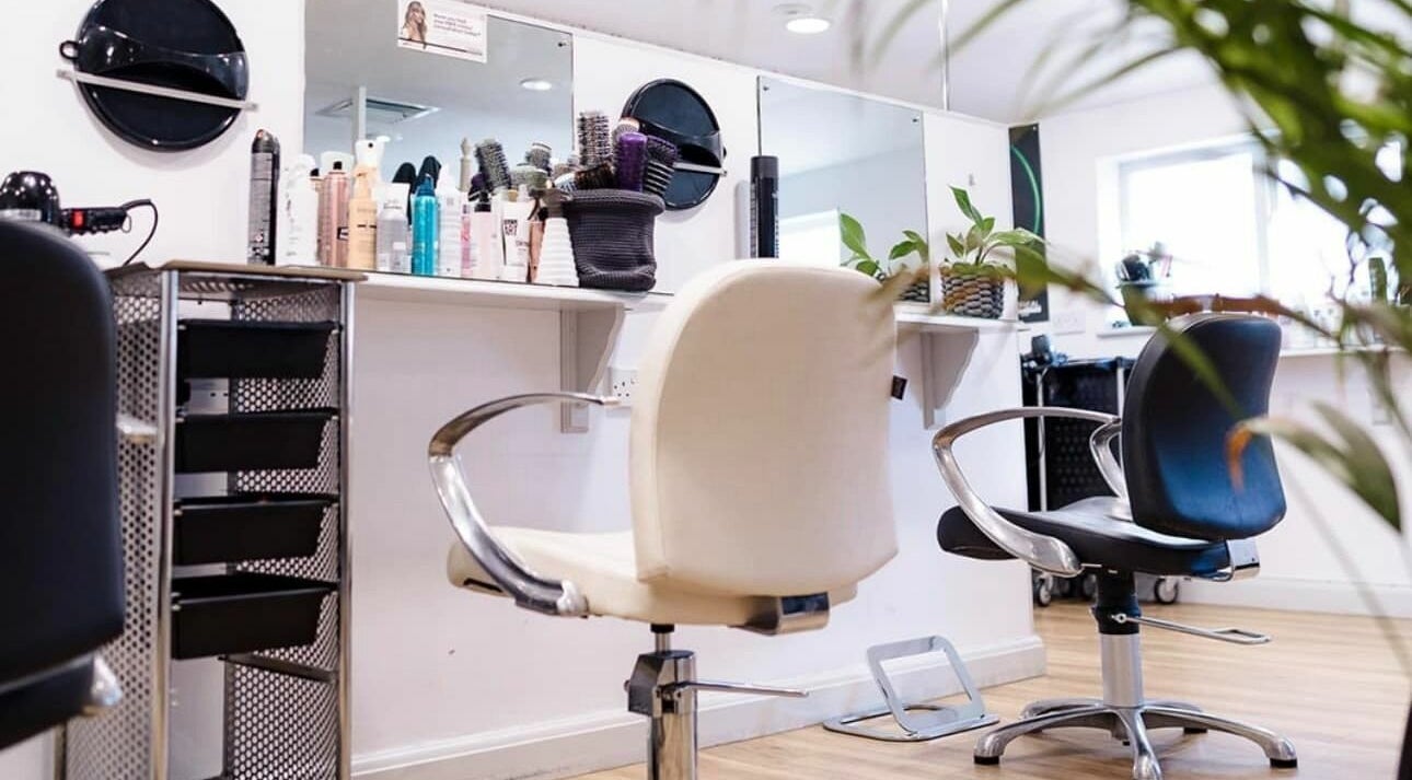Modern salon interior at Hair by Us, Saffron Walden, England, GB with stylish chairs and hair products.