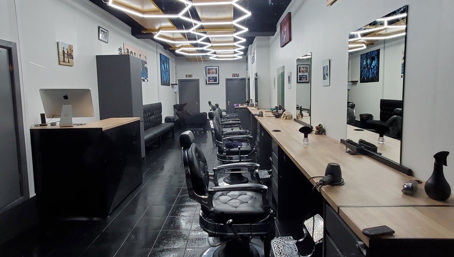 Modern interior of Sauchiehall Barbers, Glasgow, Scotland, GB, featuring sleek black chairs and stylish decor.