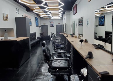 Modern interior of Sauchiehall Barbers, Glasgow, Scotland, GB, featuring sleek black chairs and stylish decor.