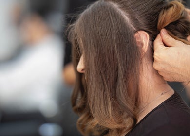 Stylist perfecting a hairstyle at Arelis Beauty Salon, Orlando, Florida, US. Close-up of skilled hands.
