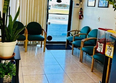 Cozy waiting area at Arelis Beauty Salon in Orlando, Florida with green chairs and plants.