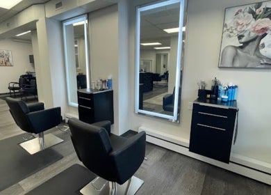 Modern styling stations at Salon Femia in Somerville, Massachusetts, US with sleek black chairs and mirrors.