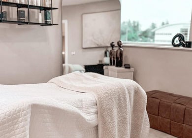 Elegant treatment room at The Glow Clinic, Cardiff Bay, GB featuring a relaxing massage bed and decor.