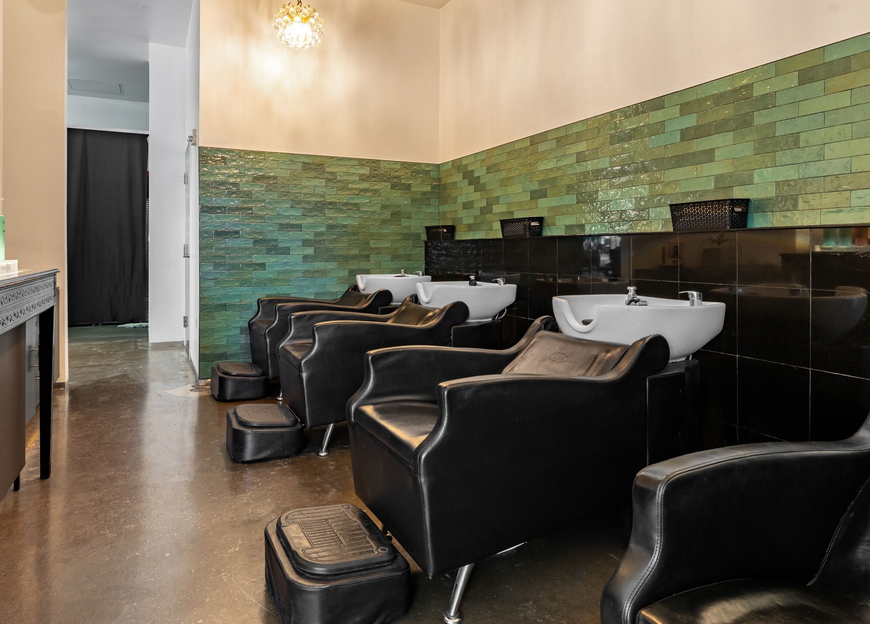 Modern wash stations at Salon Blanc the celebrities salon in Honolulu, Hawaii, US, with sleek black chairs.