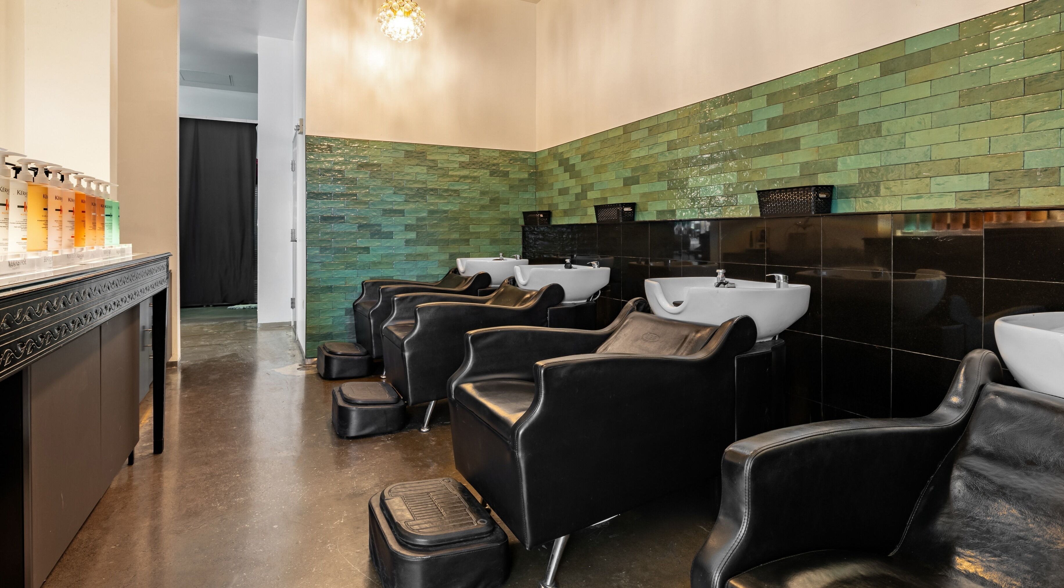 Modern wash stations at Salon Blanc the celebrities salon in Honolulu, Hawaii, US, with sleek black chairs.
