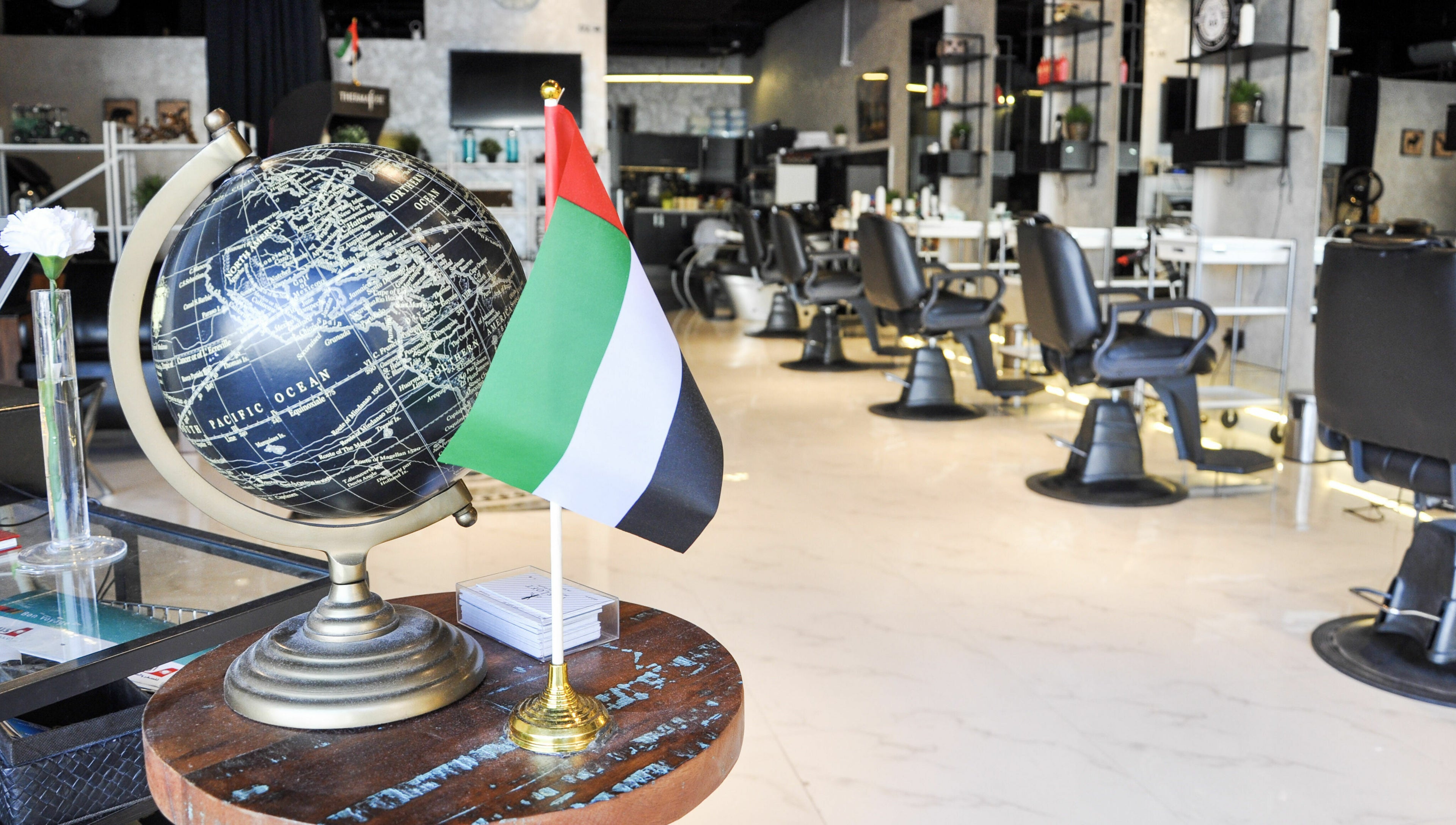 Interior of The Loft Prime Gent's Salon in Dubai, featuring a globe and the UAE flag on a table.