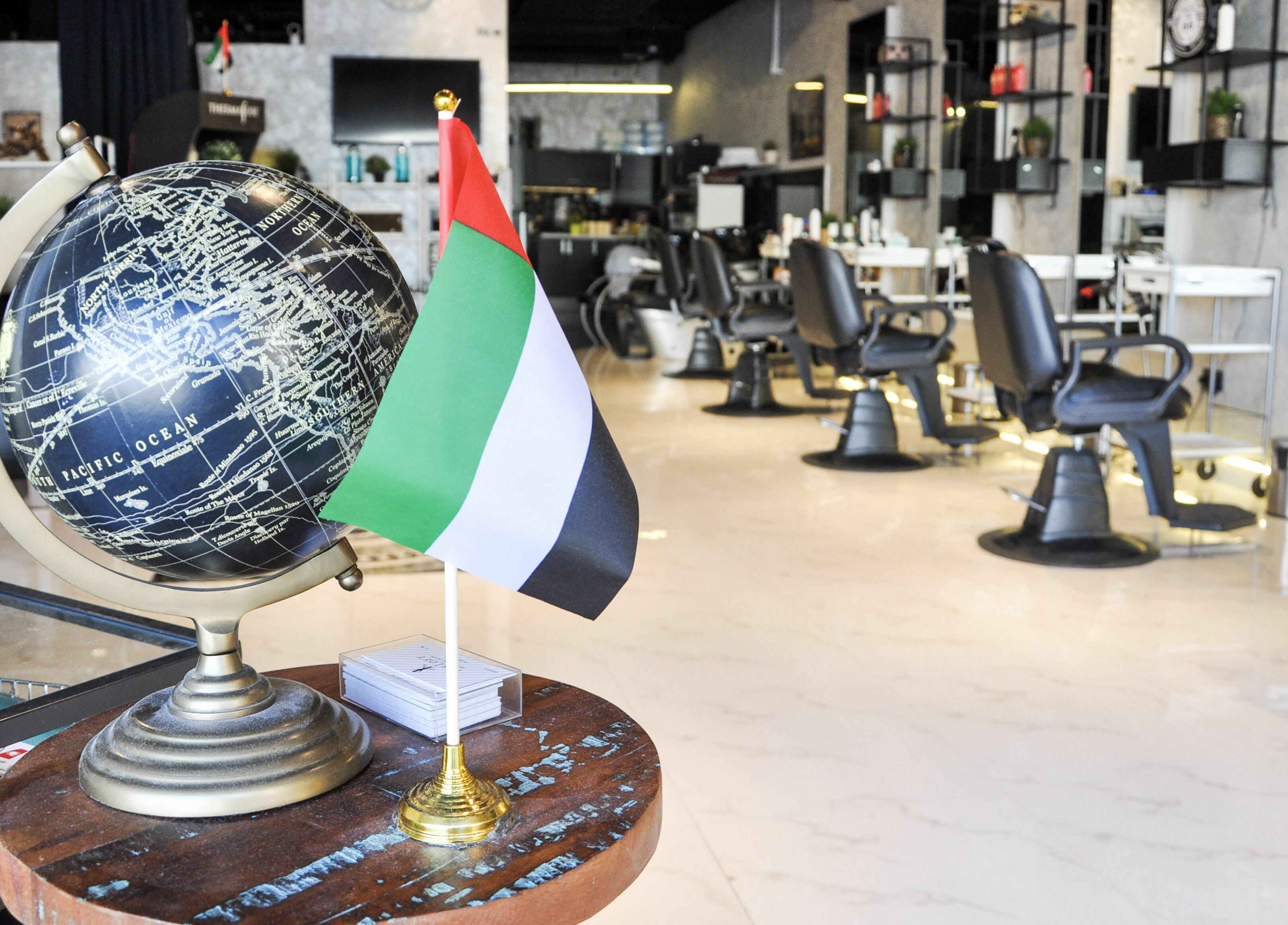 Interior of The Loft Prime Gent's Salon in Dubai, featuring a globe and the UAE flag on a table.