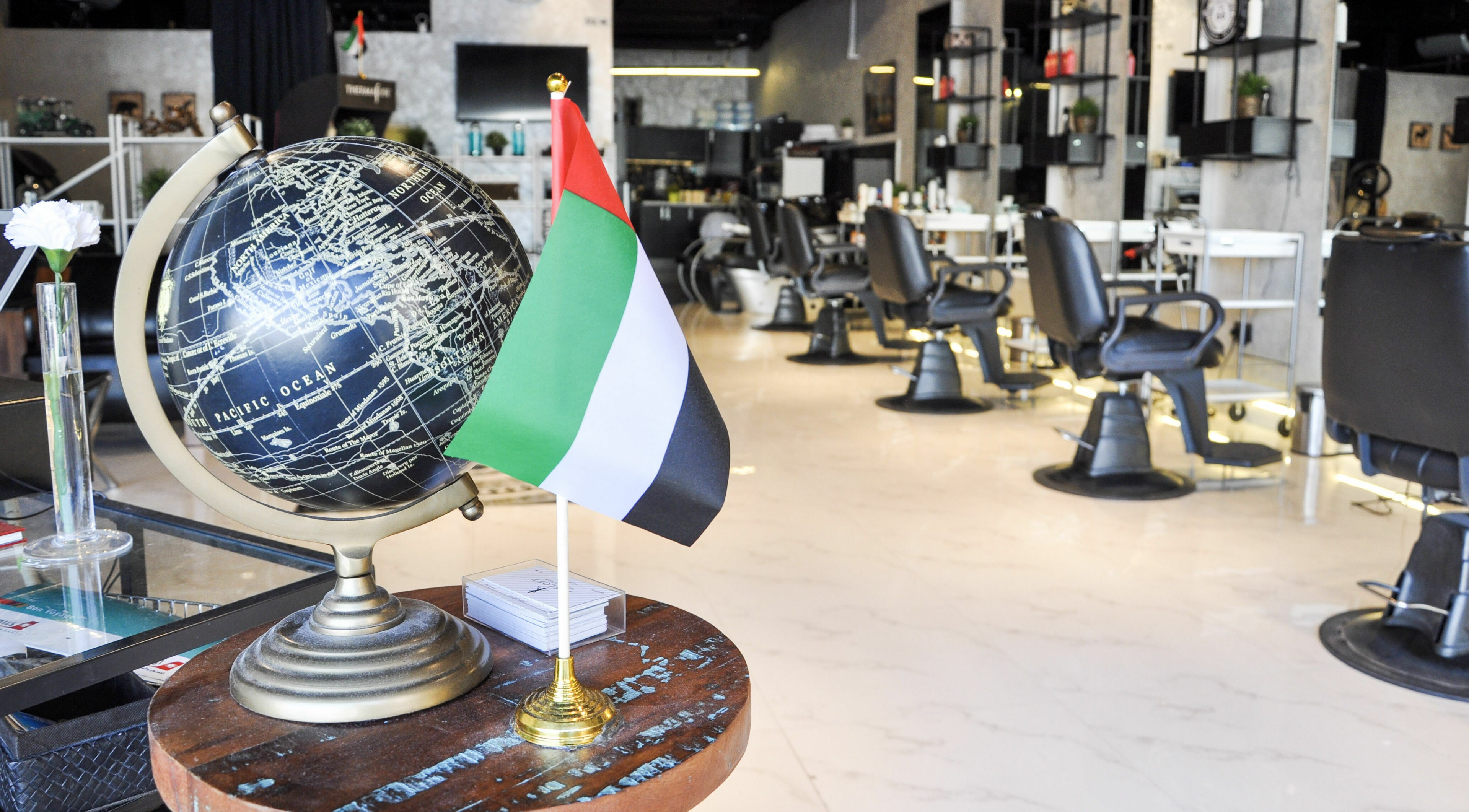 Interior of The Loft Prime Gent's Salon in Dubai, featuring a globe and the UAE flag on a table.