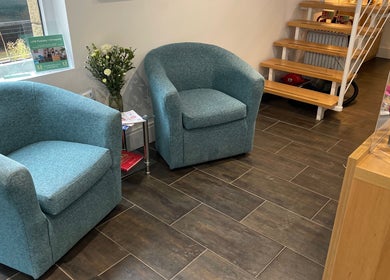 Cozy seating area at LFW Podiatry (Chiropody) Clinic - Ilkley, featuring blue armchairs and lush greenery.