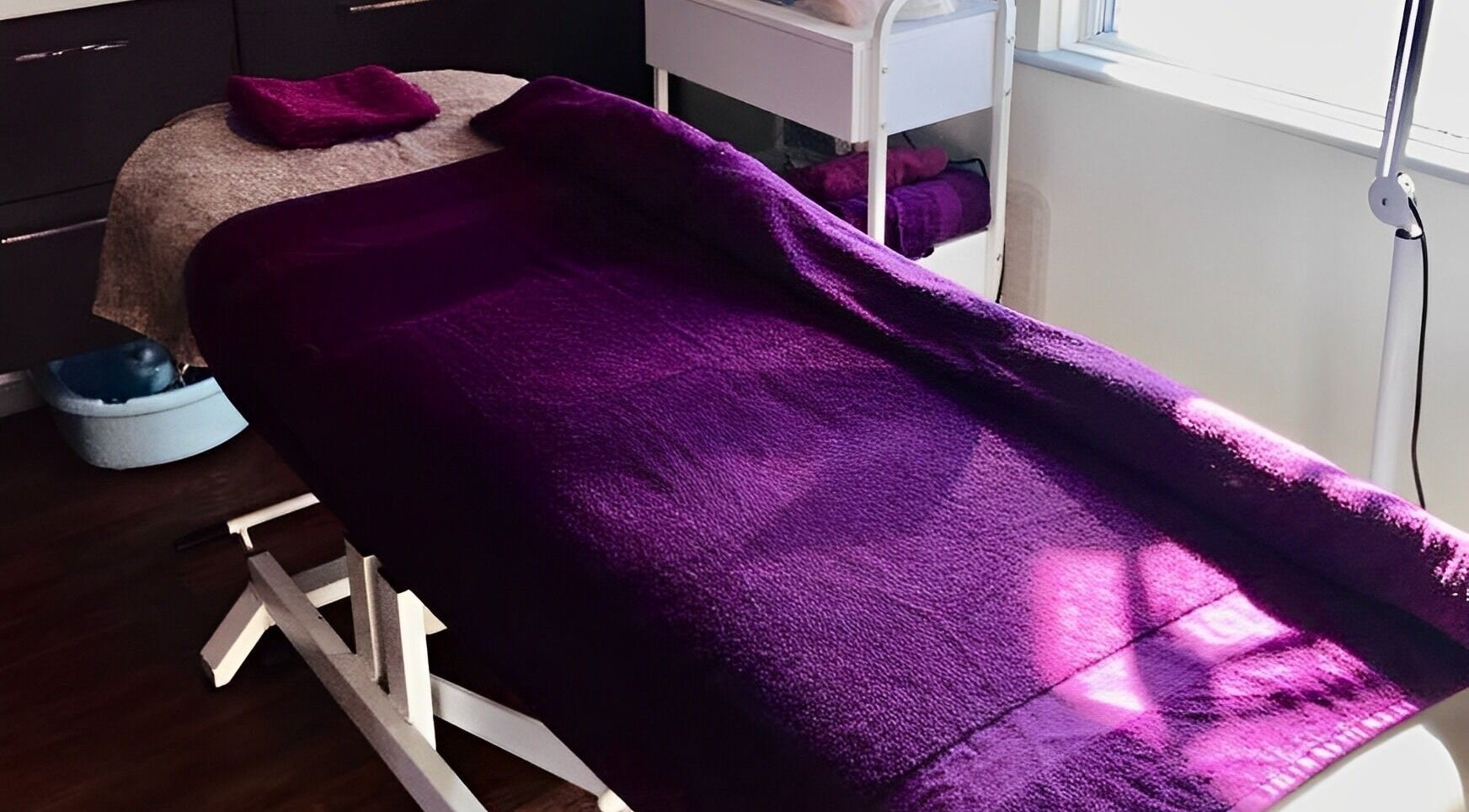 Relaxing massage bed at Amis Hair & Beauty, Riccall, England, GB, draped in rich purple fabric.