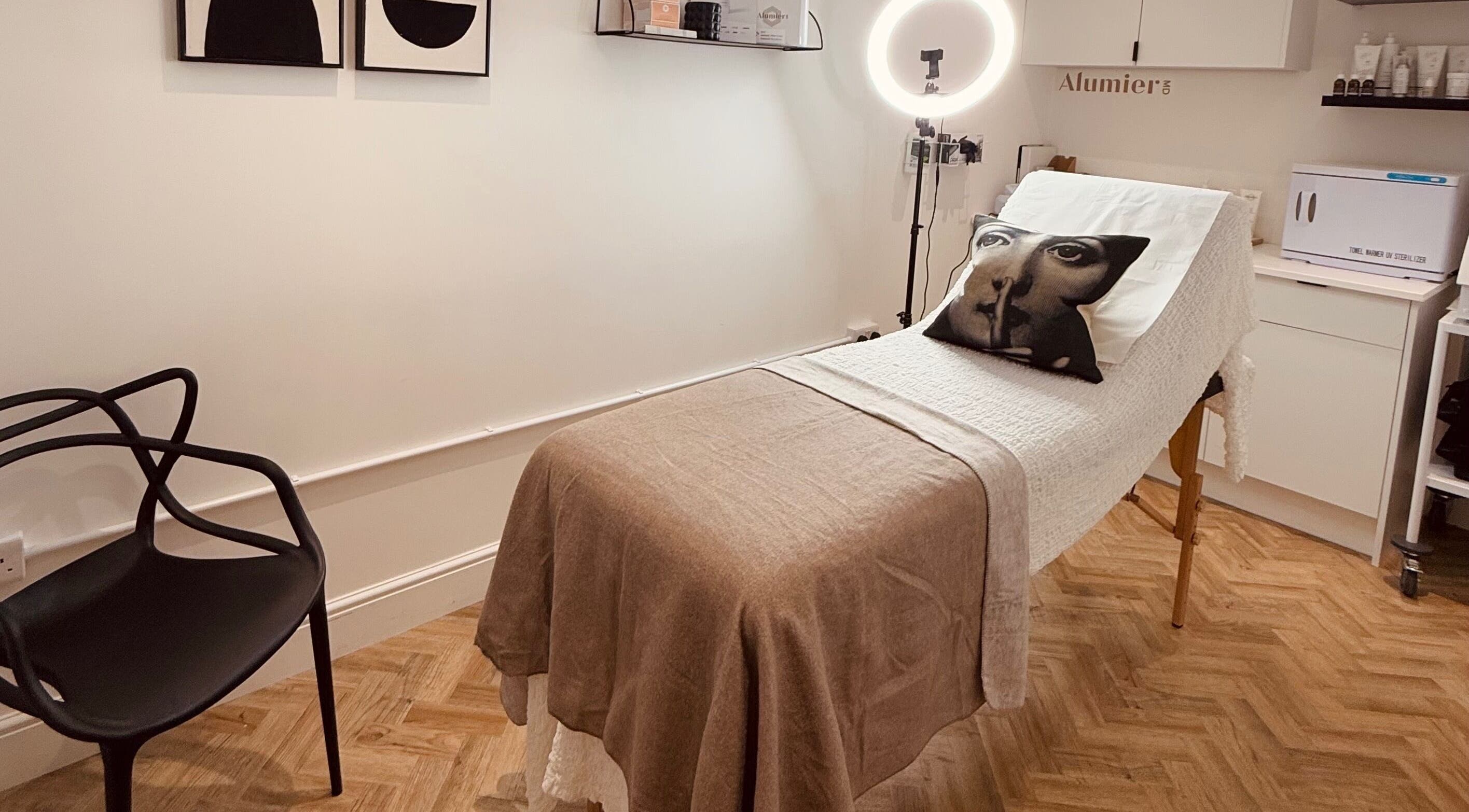 Tranquil treatment room at RE:NU Clinic, Henstead, England. Cozy bed with artistic decor for a serene experience.