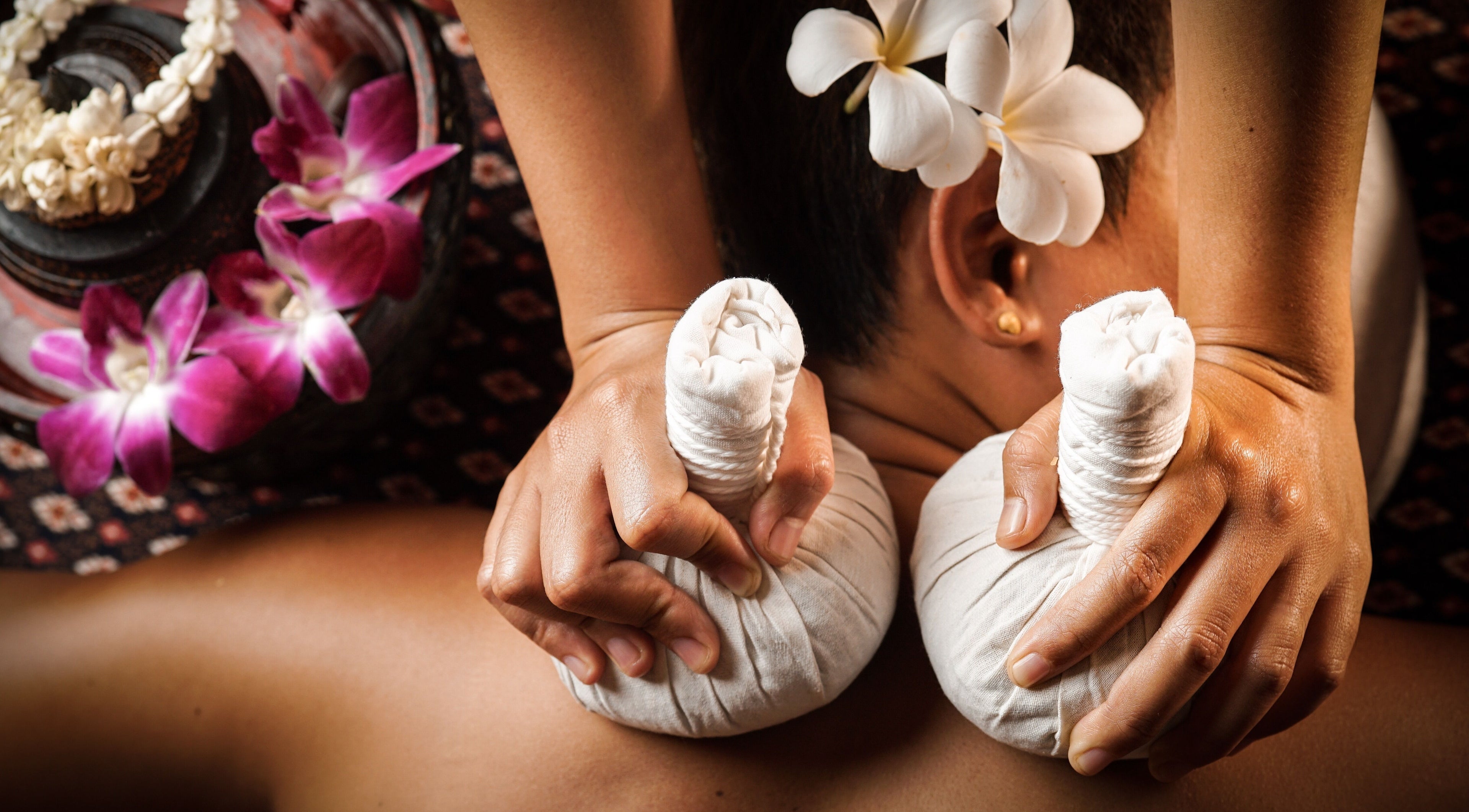 Herbal compress massage at Organic Thai Spa, Vancouver, British Columbia, CA with fragrant flowers.