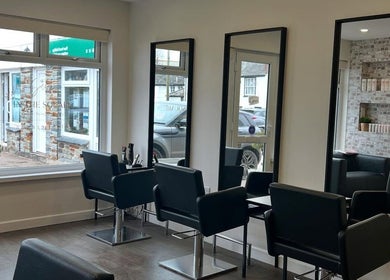 Modern salon interior at Salon in the Square, Mawnan Smith, England, GB with stylish chairs and mirrors.
