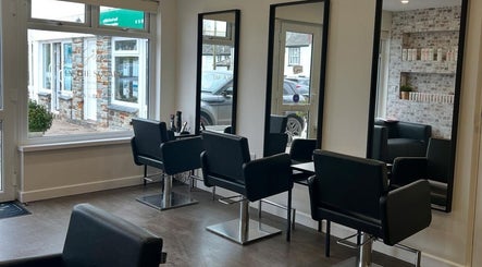 Modern hair salon interior at Salon in the Square, Mawnan Smith, England, GB with sleek styling chairs and mirrors.