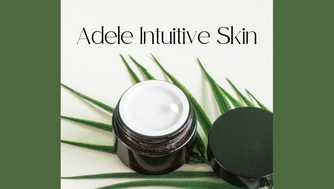 Adele Intuitive Skin Luton showcases a luxurious cream jar on lush green leaves.
