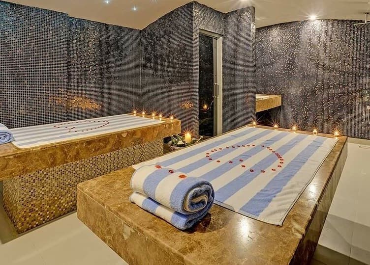 Luxurious massage room at Reborn Spa Ramee Rose Slimming Wellness Center, Manama, BH, with towels and candles.