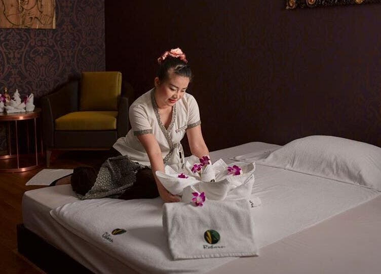 A serene spa setup with towels and orchids at Reborn Spa Ramee Rose Slimming Wellness Center, Manama, BH.