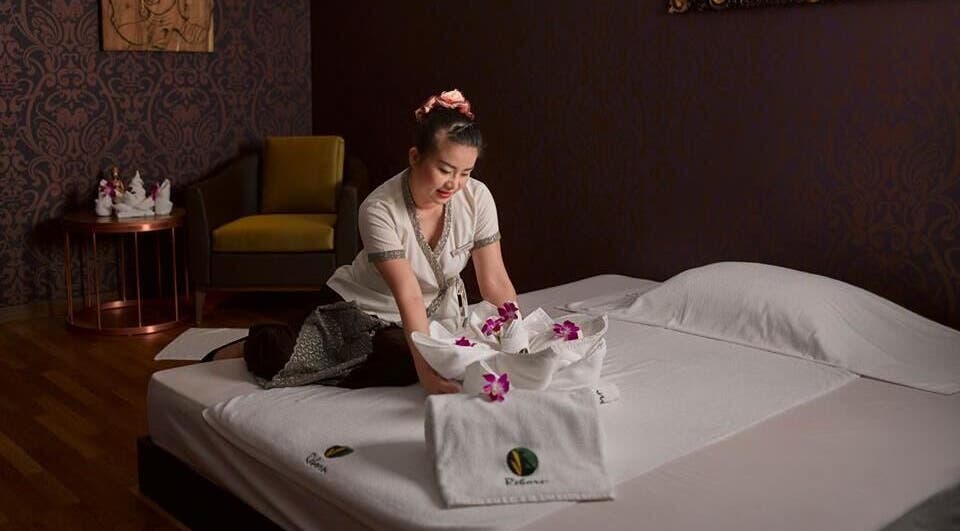 A serene spa setup with towels and orchids at Reborn Spa Ramee Rose Slimming Wellness Center, Manama, BH.