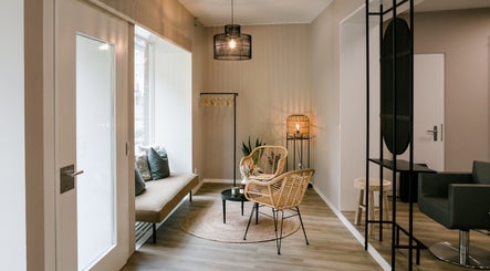 Elegant waiting area at Marios Tsikrikas Hair Artist, Zürich, featuring modern chairs and warm lighting.